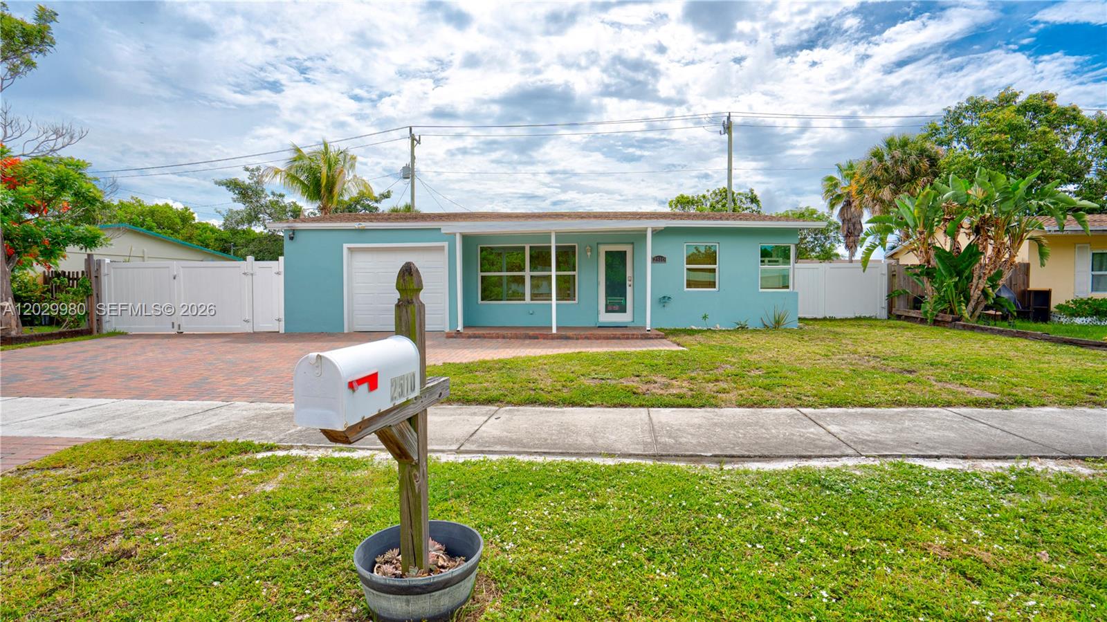 A light blue single-story house features a brick driveway, a white garage, and a mailbox — 2510 NE 9th Ave, Pompano Beach FL 33064, POMPANO BEACH, FL