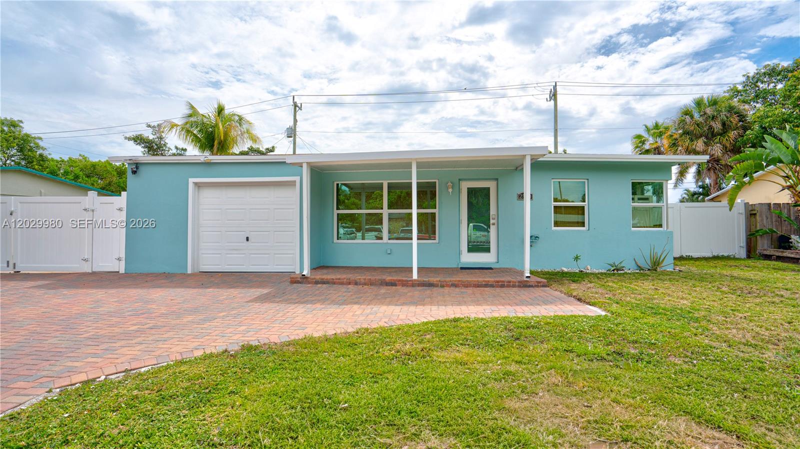 A light blue single-story house features a brick driveway, a garage, and a front porch — 2510 NE 9th Ave, Pompano Beach FL 33064, POMPANO BEACH, FL