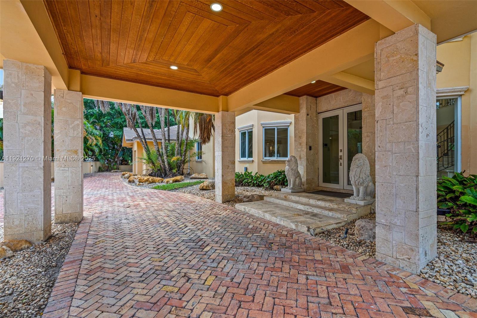 A covered brick driveway leads to a home entrance flanked by two stone lion statues — 7225 Gleneagle Dr, Miami Lakes FL 33014, MIAMI LAKES, FL