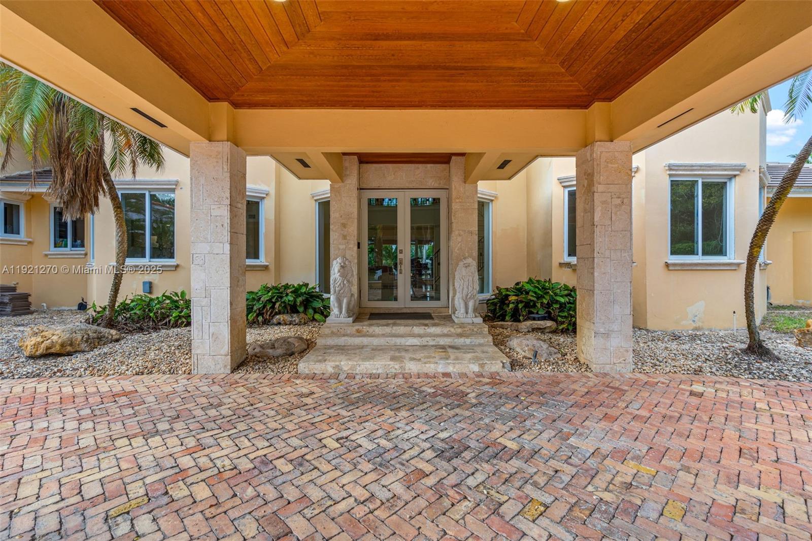 The exterior entrance features a brick driveway, stone pillars, and a wooden ceiling — 7225 Gleneagle Dr, Miami Lakes FL 33014, MIAMI LAKES, FL