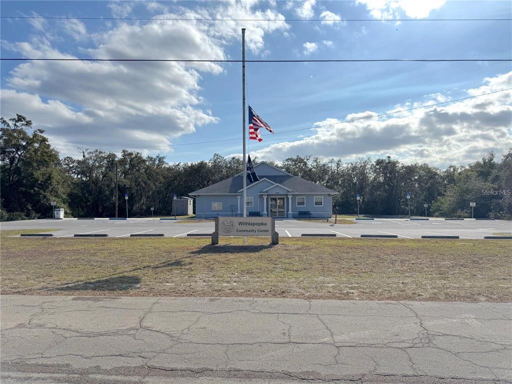 A view of the Withlapopka Community Center building with a parking lot and flagpole — 11142 E SAILFISH WAY, FLORAL CITY, FL