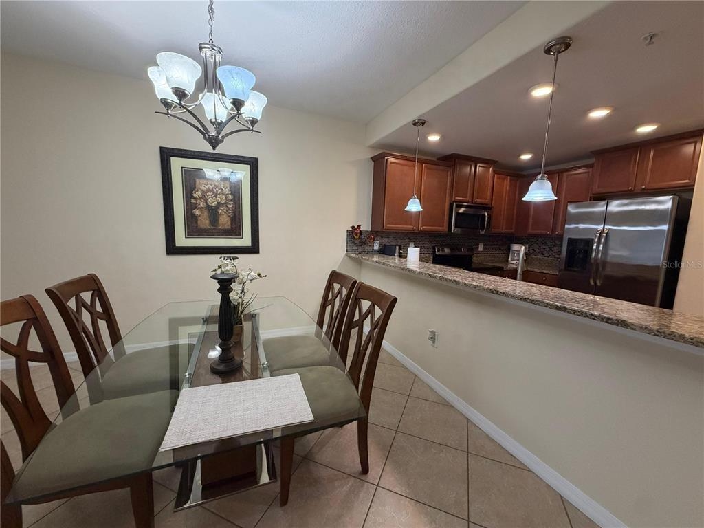 A dining area with a glass table and chairs sits adjacent to a kitchen with granite countertops — 8931 AZALEA SANDS LANE, DAVENPORT, FL