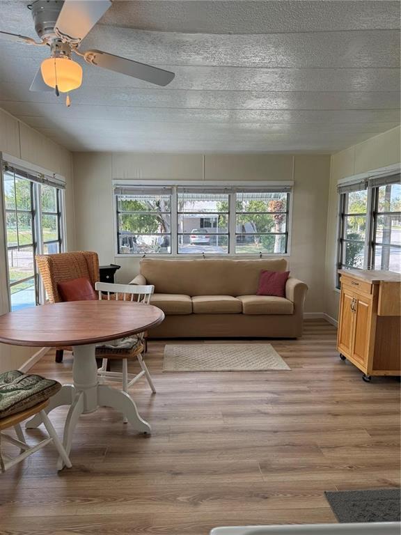 A sunroom features wood-look flooring, a ceiling fan, a sofa, and a round dining table — 1508 BLIND BROOK DRIVE, SARASOTA, FL