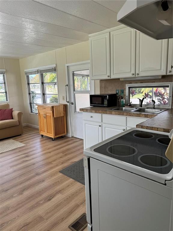 A kitchen with white cabinets and a glass-top stove opens into a living area — 1508 BLIND BROOK DRIVE, SARASOTA, FL
