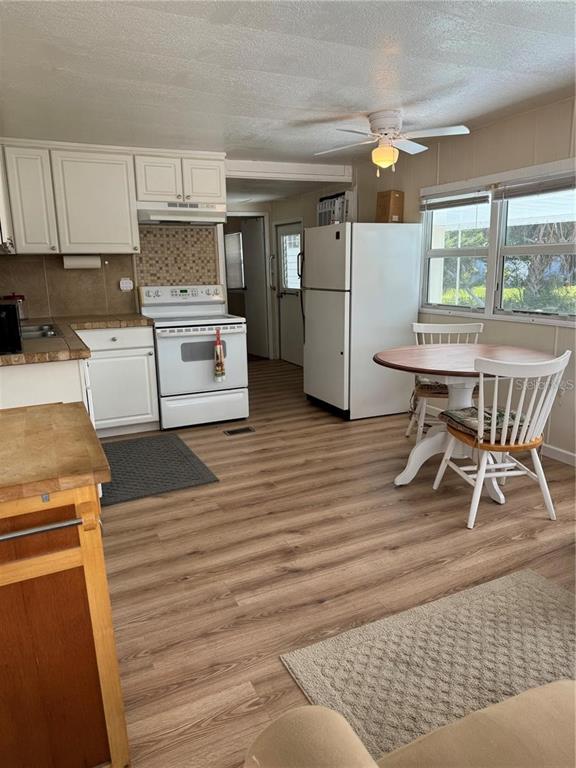 A kitchen with white cabinets, a white stove, a refrigerator, and a small dining table — 1508 BLIND BROOK DRIVE, SARASOTA, FL