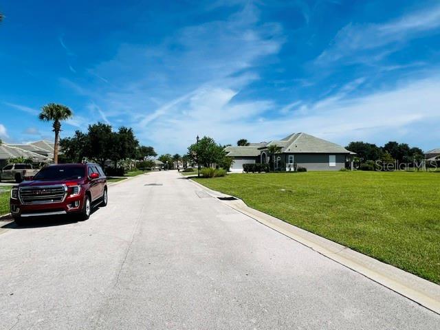 A red SUV is parked on a residential street next to a large grassy lawn — 74 LONGVIEW WAY N, PALM COAST, FL