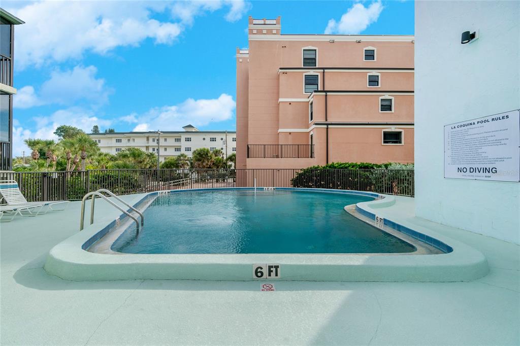 An outdoor swimming pool with a six-foot depth marker sits beside a multi-story building — 2810 N BEACH ROAD UNIT 108, ENGLEWOOD, FL