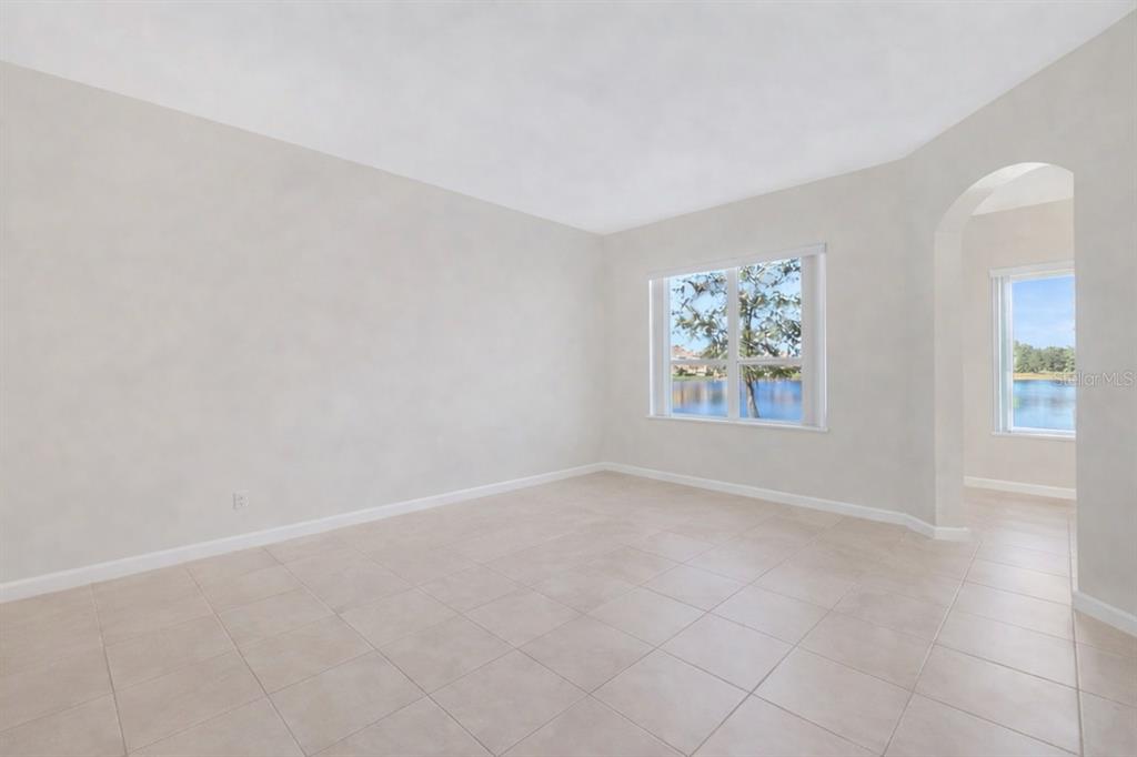 An empty room with light-colored tile flooring, white walls, and windows overlooking a lake — 3821 SHOREVIEW DRIVE, KISSIMMEE, FL