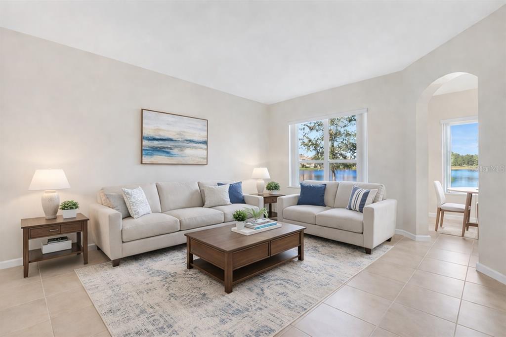 A living room with beige sofas, a wooden coffee table, and a view of a lake — 3821 SHOREVIEW DRIVE, KISSIMMEE, FL