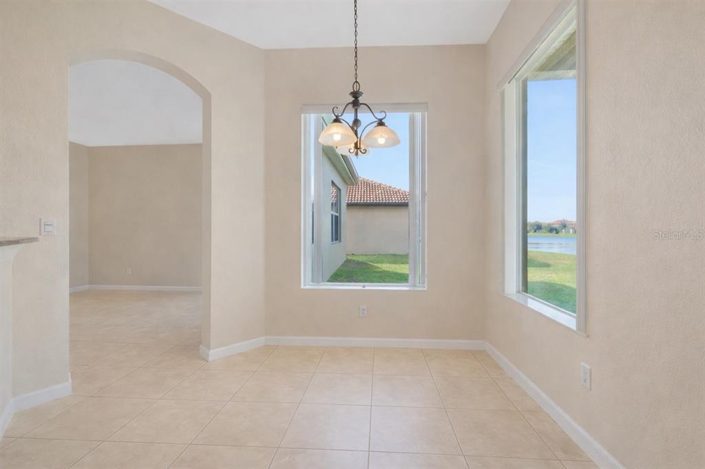 An empty dining area with tile floors, a chandelier, and windows overlooking a lake — 3821 SHOREVIEW DRIVE, KISSIMMEE, FL