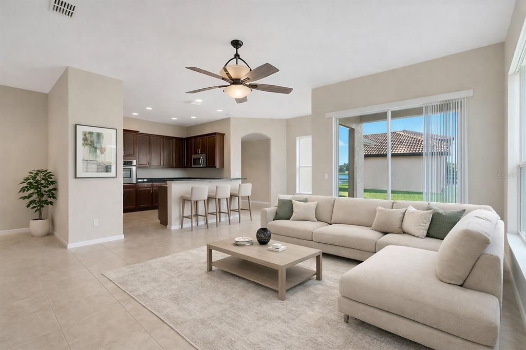 An open-concept living room features a beige sectional sofa, a coffee table, and a kitchen — 3821 SHOREVIEW DRIVE, KISSIMMEE, FL