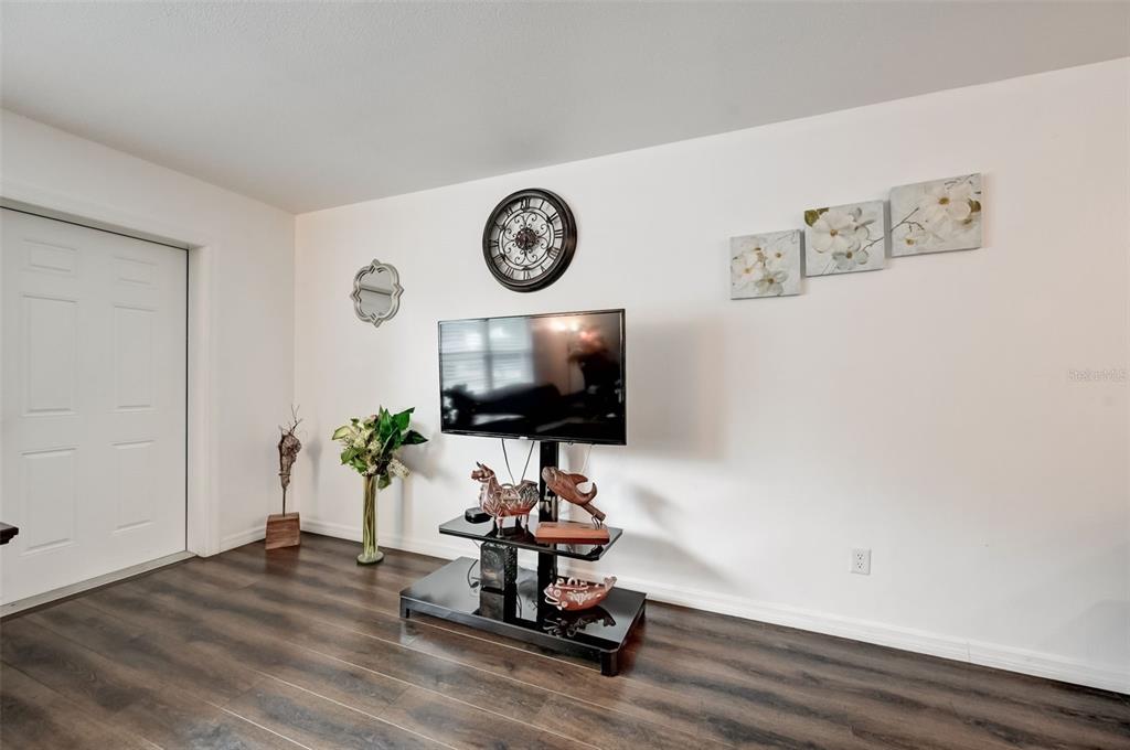 A living room features a television on a black stand, wall art, and wood-look flooring — 618 S OSPREY AVENUE, SARASOTA, FL