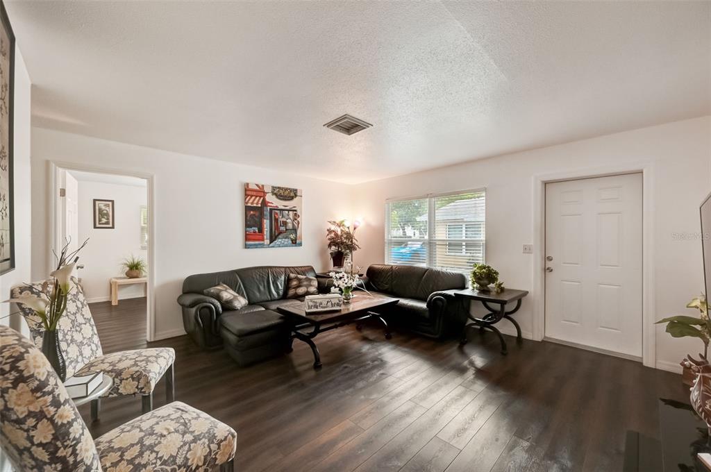 A living room features dark wood flooring, two black leather sofas, and floral patterned armchairs — 618 S OSPREY AVENUE, SARASOTA, FL
