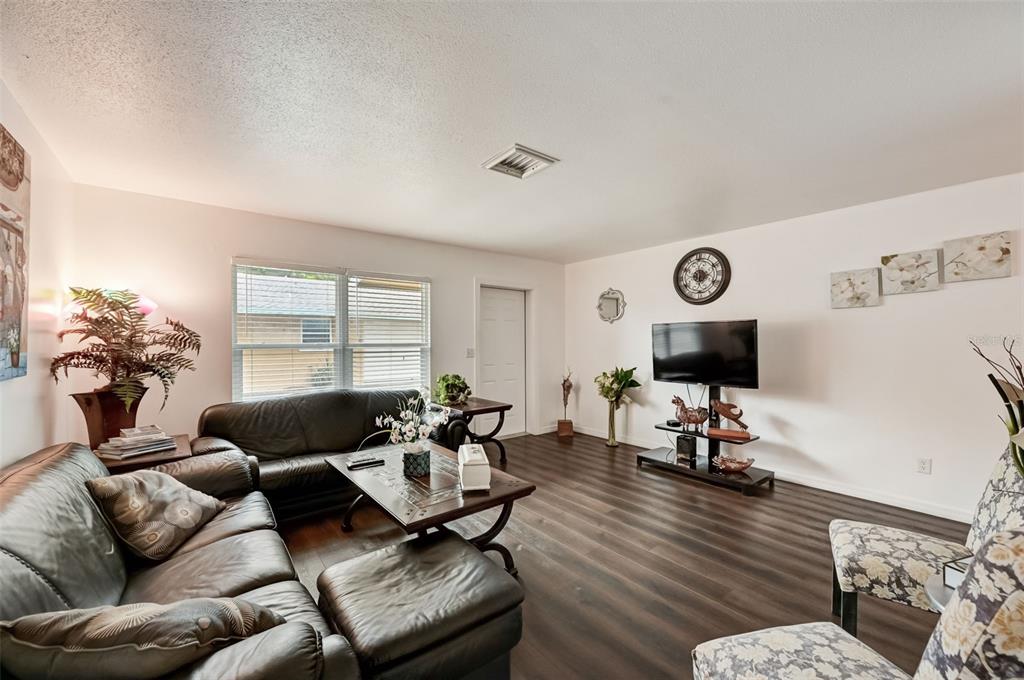 A living room features dark wood-look flooring, a leather sofa, and a wall-mounted television — 618 S OSPREY AVENUE, SARASOTA, FL
