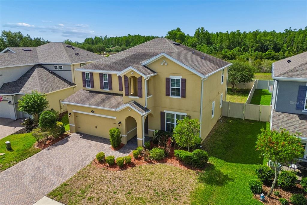 An aerial view of a two-story tan house with a paved driveway and shingled roof — 1192 MULTIFLORA LOOP, LUTZ, FL