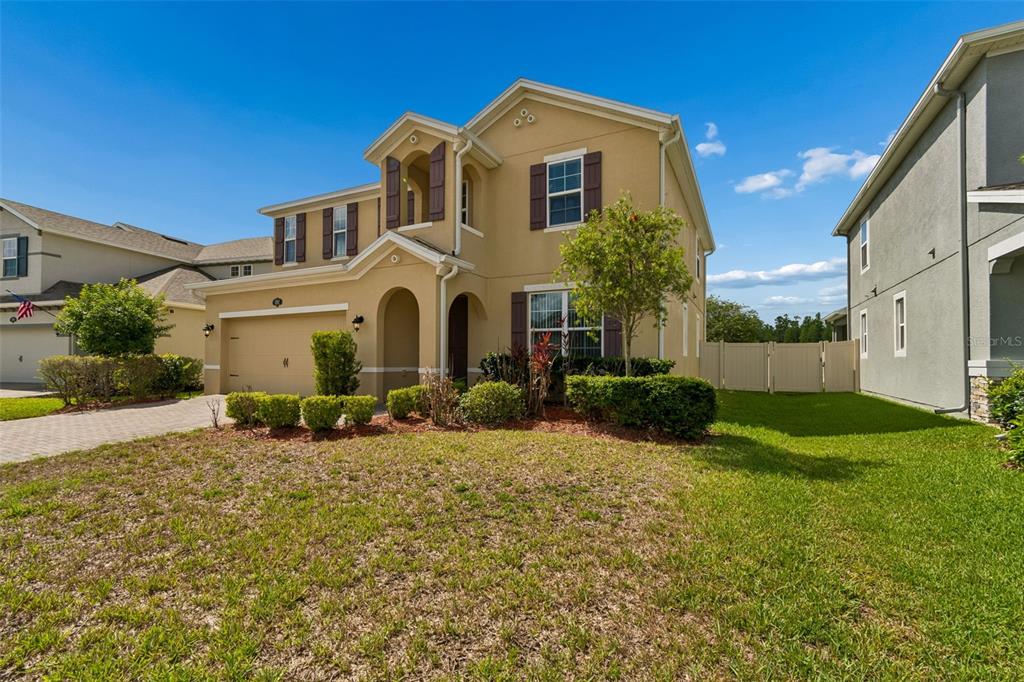 A two-story tan house with a two-car garage and a front yard — 1192 MULTIFLORA LOOP, LUTZ, FL