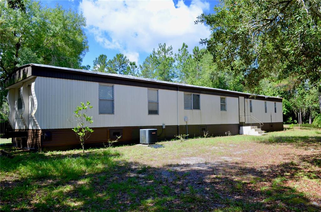 A single-wide mobile home with beige siding and brown trim sits on a grassy lot — 33135 FOREST RIDGE ROAD, DELAND, FL