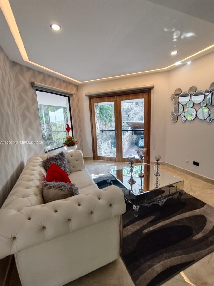 A living room features a tufted white sofa, mirrored coffee table, and a decorative wall mirror — Via Dapa Km1, Co 760001, Co