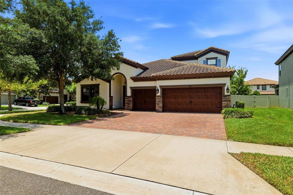 A single-story house with a tile roof, brick driveway, and a three-car garage — 2451 SLADE AVENUE, ODESSA, FL