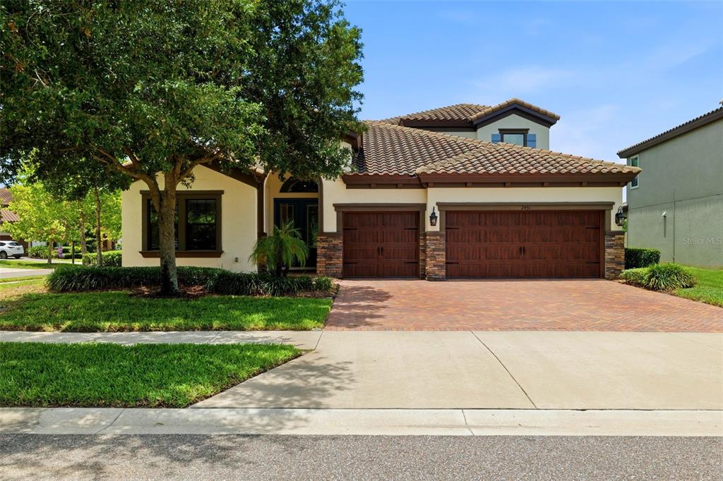 A two-story house with a tile roof, brick paver driveway, and a three-car garage — 2451 SLADE AVENUE, ODESSA, FL