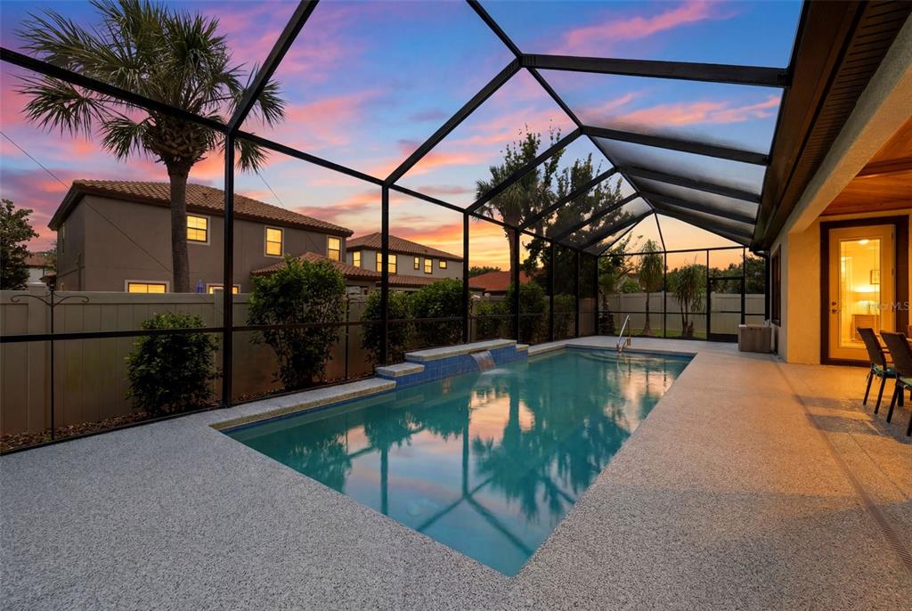 A screened-in swimming pool with a water feature sits on a patio at sunset — 2451 SLADE AVENUE, ODESSA, FL