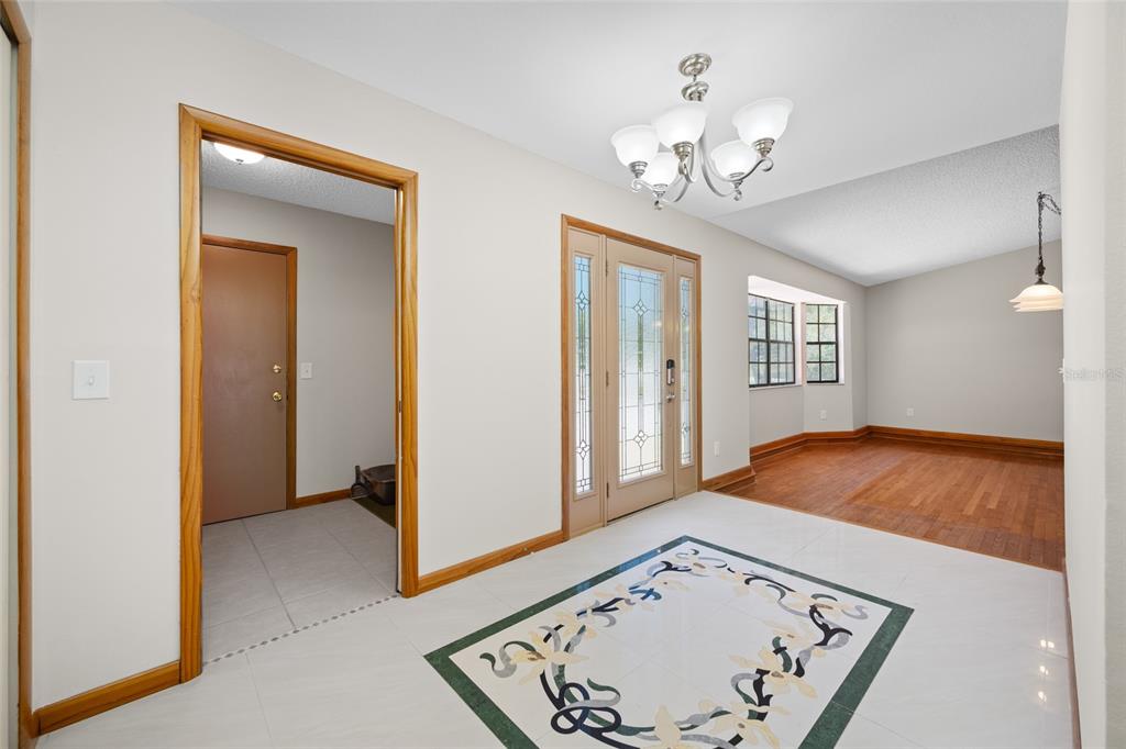 An entryway with white tile floors, a decorative inlay, and a doorway to a room — 2409 OSPREY AVENUE, PALM HARBOR, FL