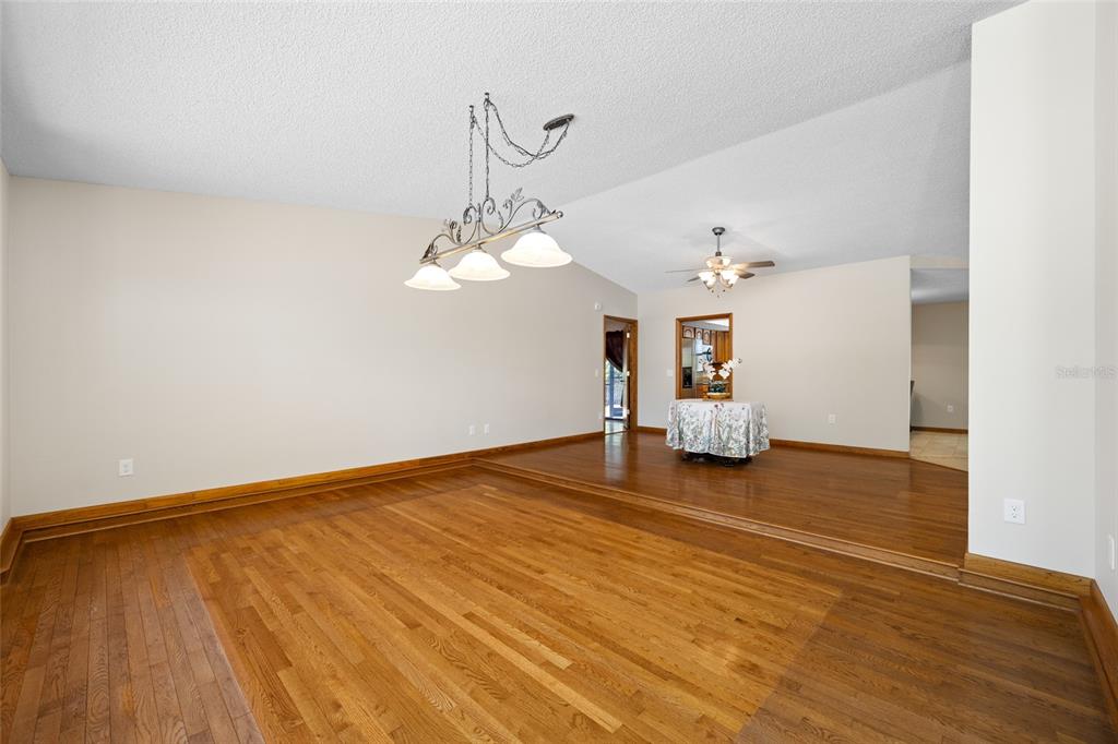A sunken living room features hardwood floors, a chandelier, and a raised dining area — 2409 OSPREY AVENUE, PALM HARBOR, FL