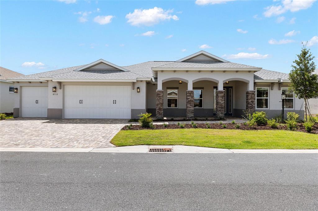 A single-story house features a three-car garage, stone-accented columns, and a covered front porch — 8512 SW 101ST AVENUE, OCALA, FL