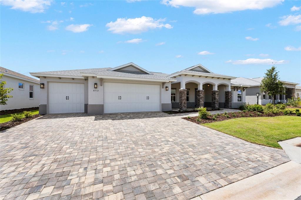 A single-story house with a paved driveway, three-car garage, and a stone-pillared covered entryway — 8512 SW 101ST AVENUE, OCALA, FL