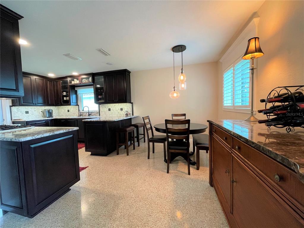 A kitchen features dark wood cabinets, white quartz countertops, and light-colored speckled flooring — 17045 DOLPHIN DRIVE, NORTH REDINGTON BEACH, FL