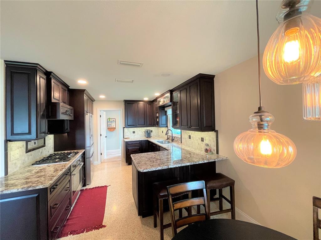 A kitchen features dark wood cabinets, white marble-look countertops, and light-colored terrazzo flooring — 17045 DOLPHIN DRIVE, NORTH REDINGTON BEACH, FL