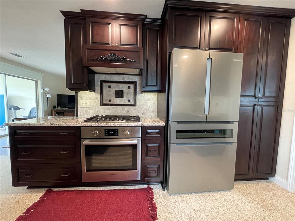 A kitchen features dark wood cabinets, white marble-look countertops, and light-colored terrazzo flooring — 17045 DOLPHIN DRIVE, NORTH REDINGTON BEACH, FL
