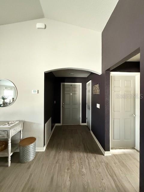 A hallway with light wood flooring leads to a gray door under an arched entryway — 5497 SE 91ST PLACE, OCALA, FL