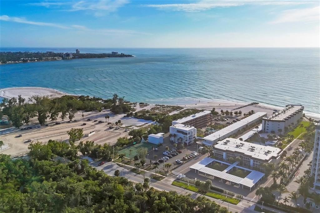 An aerial view of a coastal resort featuring multiple buildings, a parking lot, and beach access — 2100 BENJAMIN FRANKLIN DRIVE UNIT 205, SARASOTA, FL