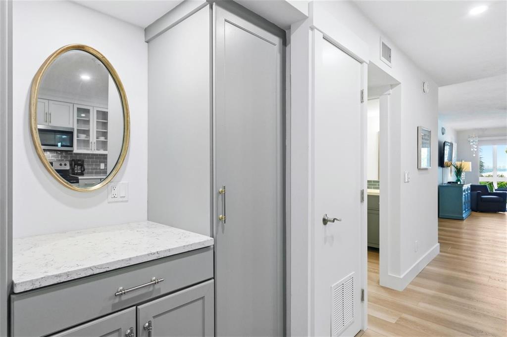 A hallway features gray cabinetry with a white countertop, a gold-framed mirror, and wood flooring — 2100 BENJAMIN FRANKLIN DRIVE UNIT 205, SARASOTA, FL