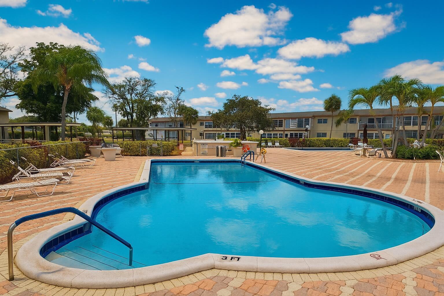 A swimming pool with a shallow entry area surrounded by a paved deck and palm trees — 550 NW 78th Terrace # 107, Margate FL 33063, MARGATE, FL