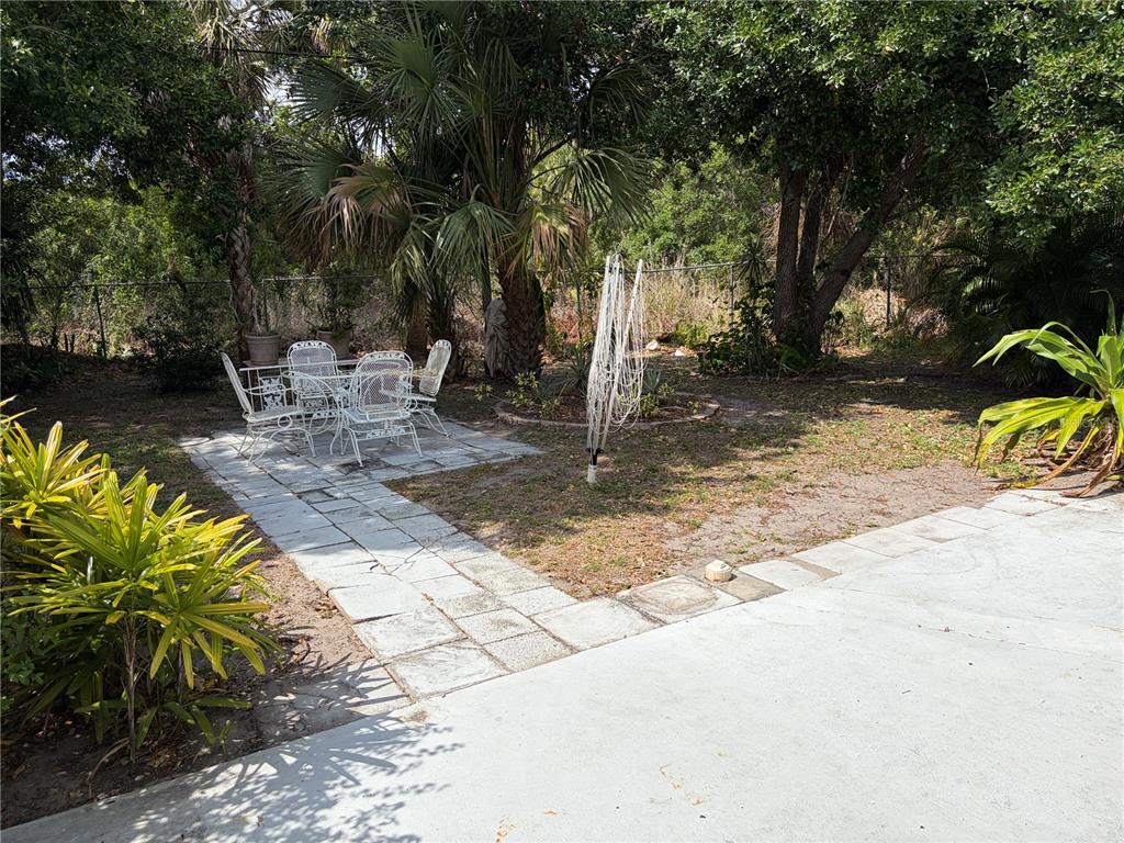A backyard features a stone patio with a white metal dining set and a clothesline — 1451 BURNING TREE STREET, SARASOTA, FL