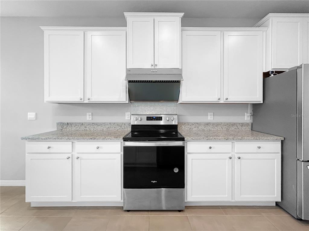 A kitchen features white cabinets, granite countertops, and stainless steel appliances — 503 158TH STREET E, BRADENTON, FL