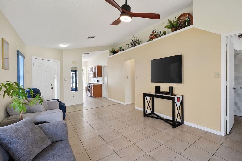 A living room features tile floors, a ceiling fan, and a wall-mounted television — 6264 PEACOCK RUN, LAKELAND, FL