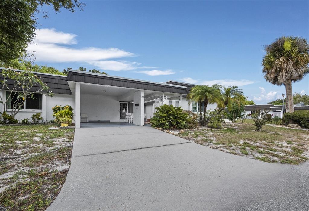 A single-story house with a white exterior, a flat roof, and a concrete driveway — 3828 BLUE STONE WAY UNIT 77, SARASOTA, FL