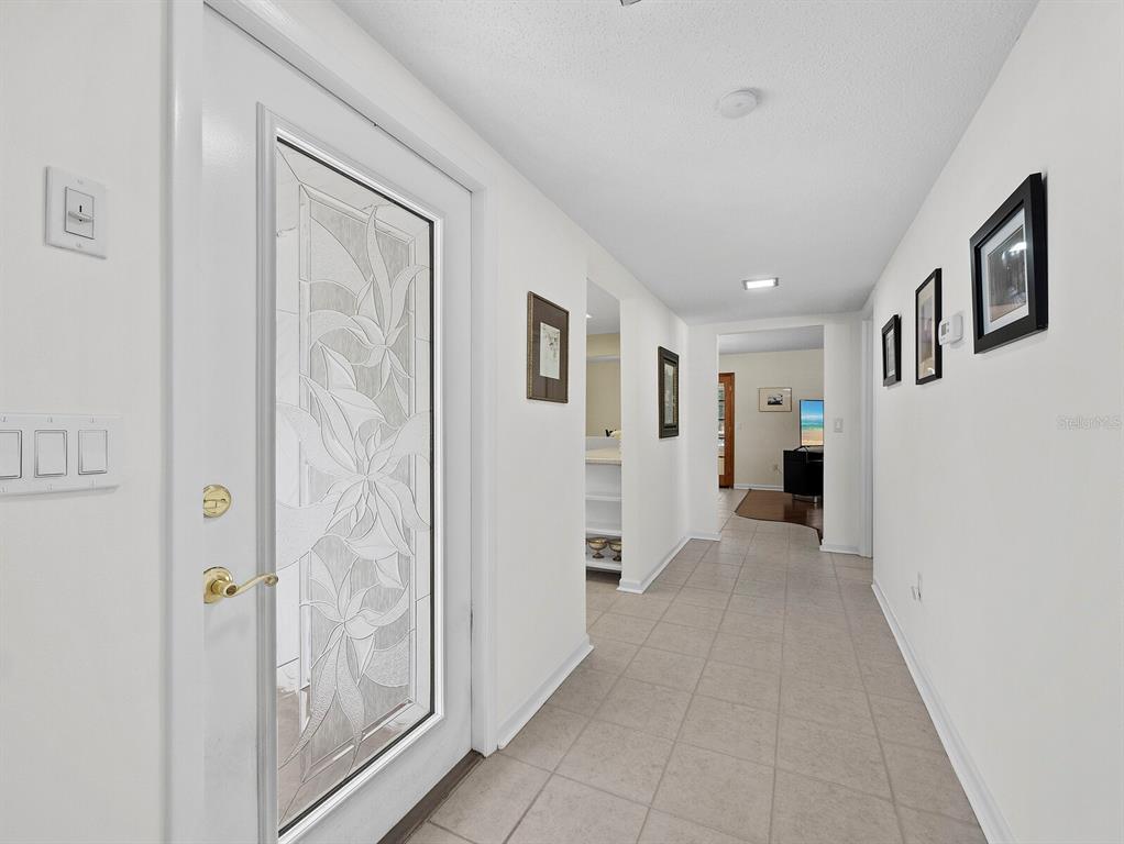 A bright entryway features a white door with decorative glass, tile flooring, and white walls — 3828 BLUE STONE WAY UNIT 77, SARASOTA, FL
