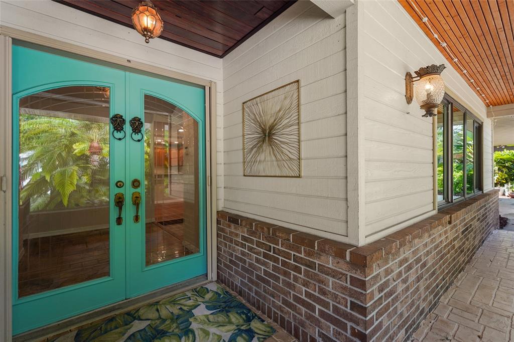A turquoise double front door with glass panels sits beside a brick and siding wall — 3781 COUNTRYSIDE ROAD, SARASOTA, FL