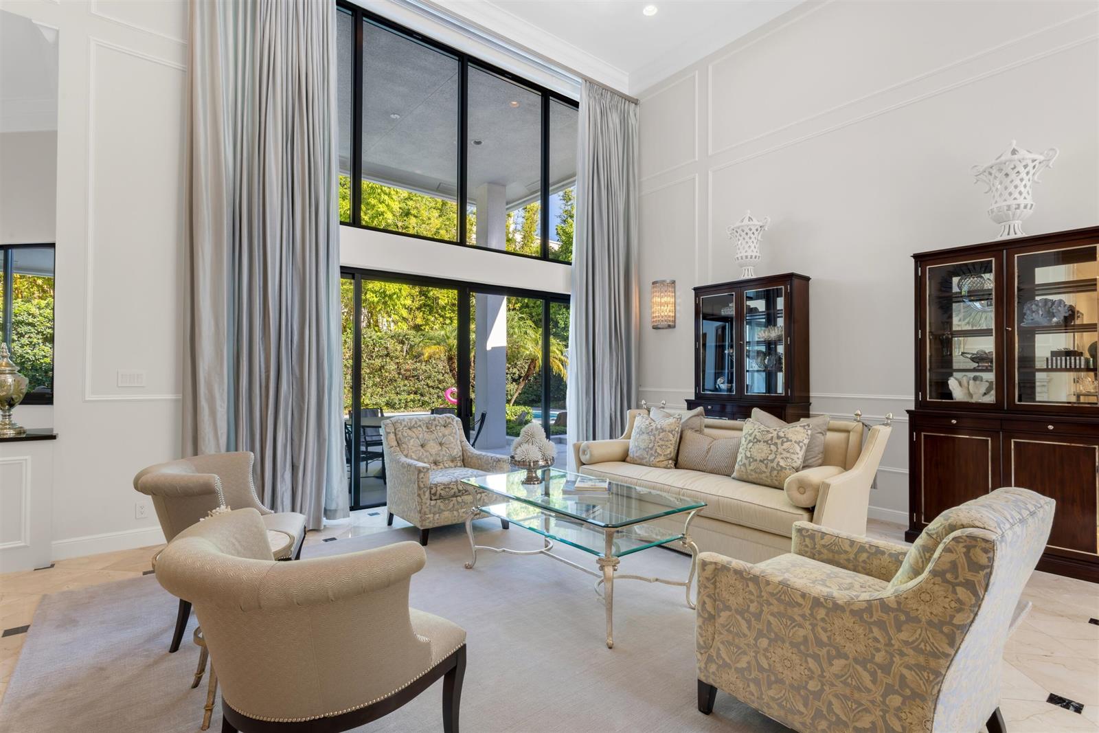 A living room features tall windows, light-colored furniture, and a view of a backyard pool — 4275 Sanctuary Lane, Boca Raton FL 33431, BOCA RATON, FL