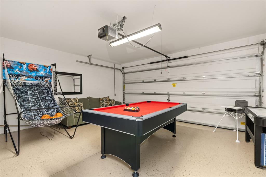 A garage converted into a game room featuring a pool table, basketball game, and sofa — 756 SCRUB JAY WAY, DAVENPORT, FL