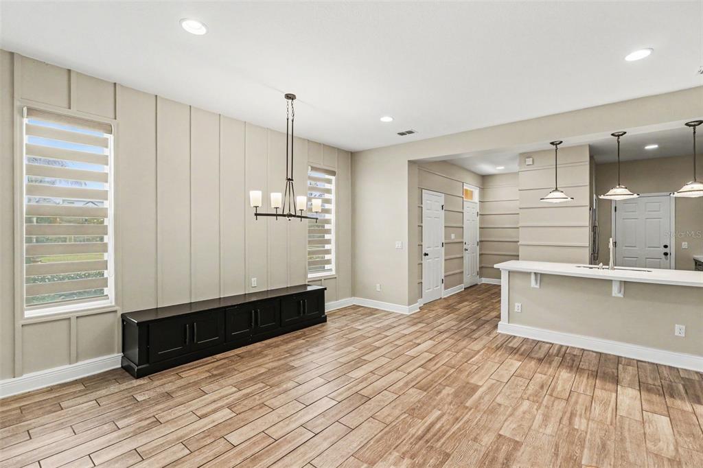 A dining area with vertical wall paneling, a black console, and wood-look tile flooring — 13500 FOUNTAINBLEAU DRIVE, CLERMONT, FL