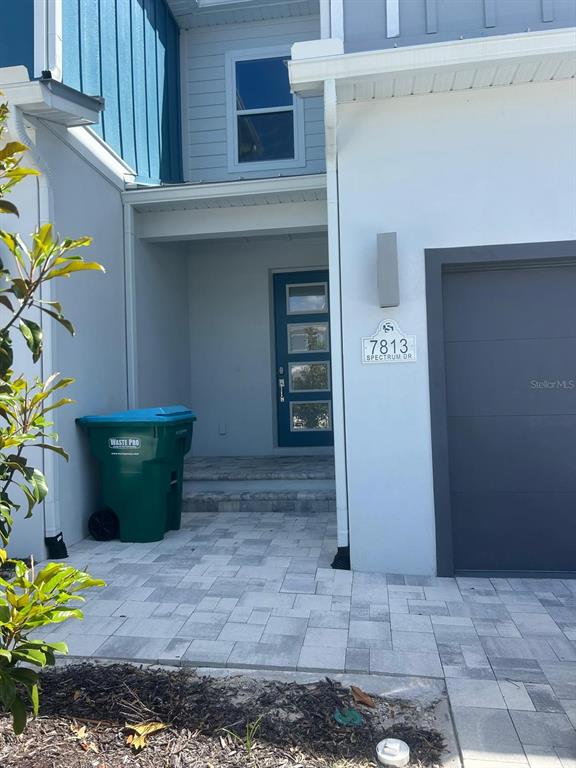 The exterior of a house features a blue front door, a garage, and a paved walkway — 7813 SPECTRUM DRIVE, REUNION, FL