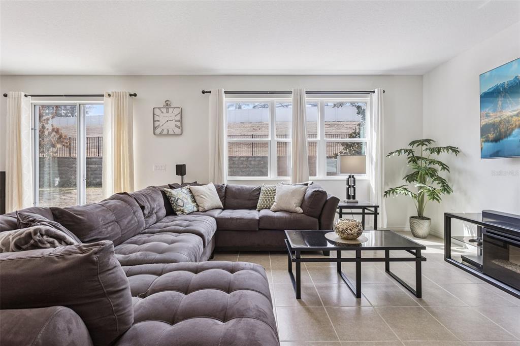 A living room features a large gray sectional sofa, a coffee table, and tile flooring — 11437 WISHING WELL LANE, CLERMONT, FL