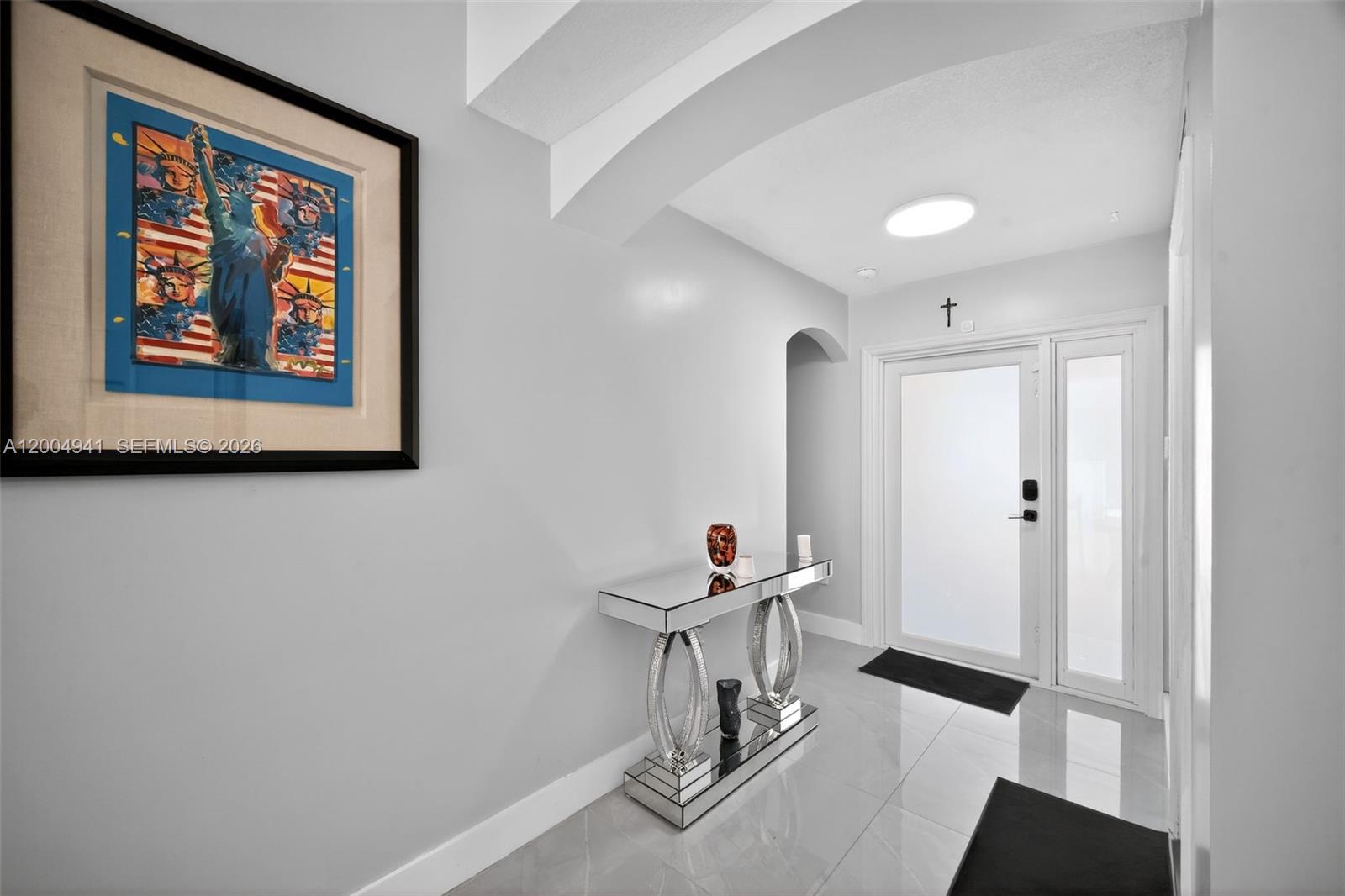 A bright entryway features light gray walls, a mirrored console table, and a glass-paneled door — 14471 SW 136th Pl, Miami FL 33186, MIAMI, FL