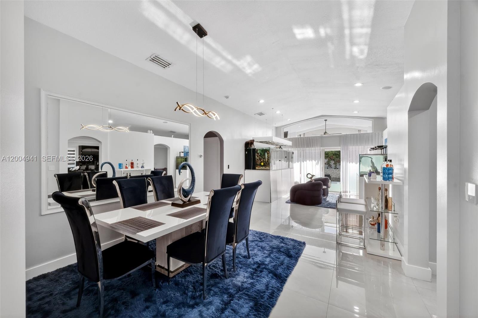 A dining room features a white table, dark chairs, a blue rug, and large mirrors — 14471 SW 136th Pl, Miami FL 33186, MIAMI, FL