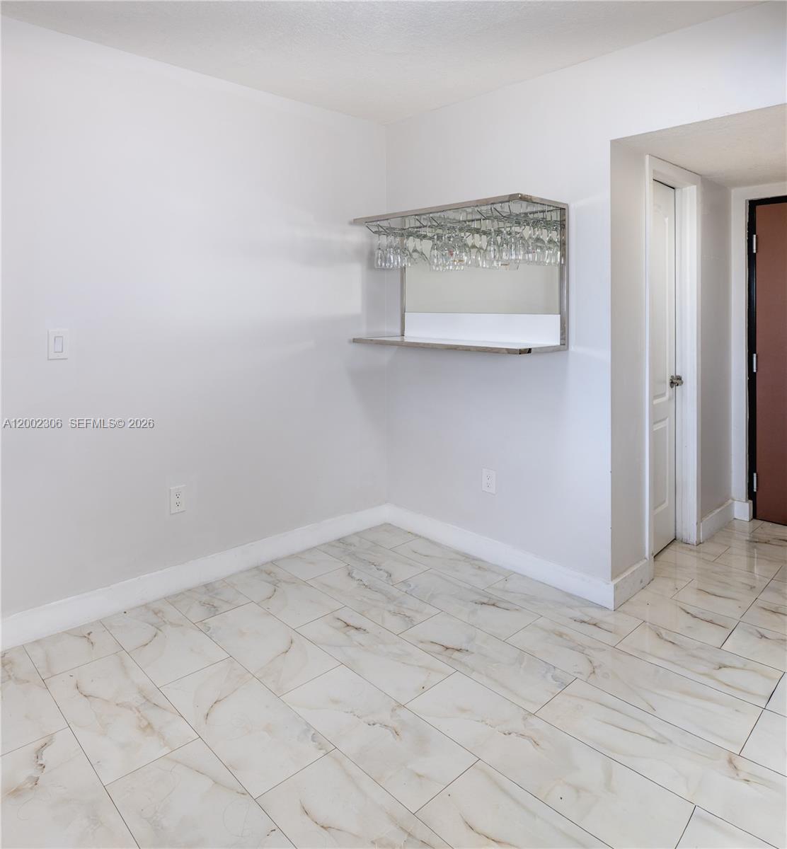A room with white walls, marble-look tile flooring, and a wall-mounted glass bar shelf — 300 NW 42nd Ave # 610, Miami FL 33126, MIAMI, FL